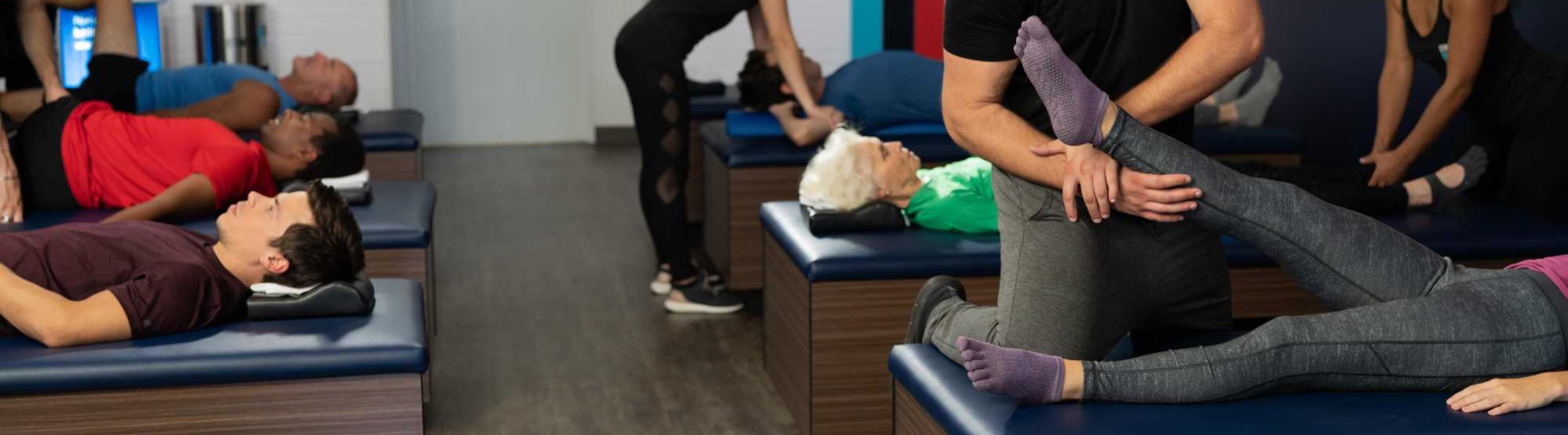 StretchLab attendees being assisted by flexologists in stretching their legs